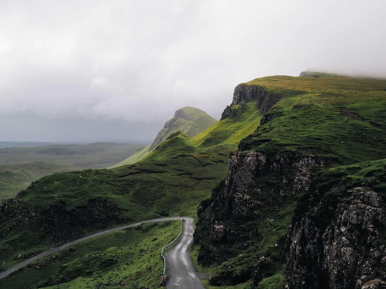 A winding path through green, mist-covered hills