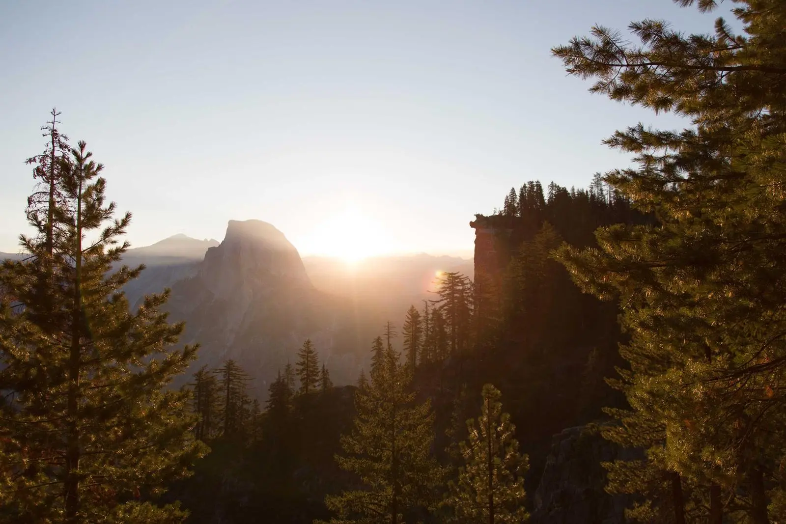 Sunrise breaking through trees in a mountain valley